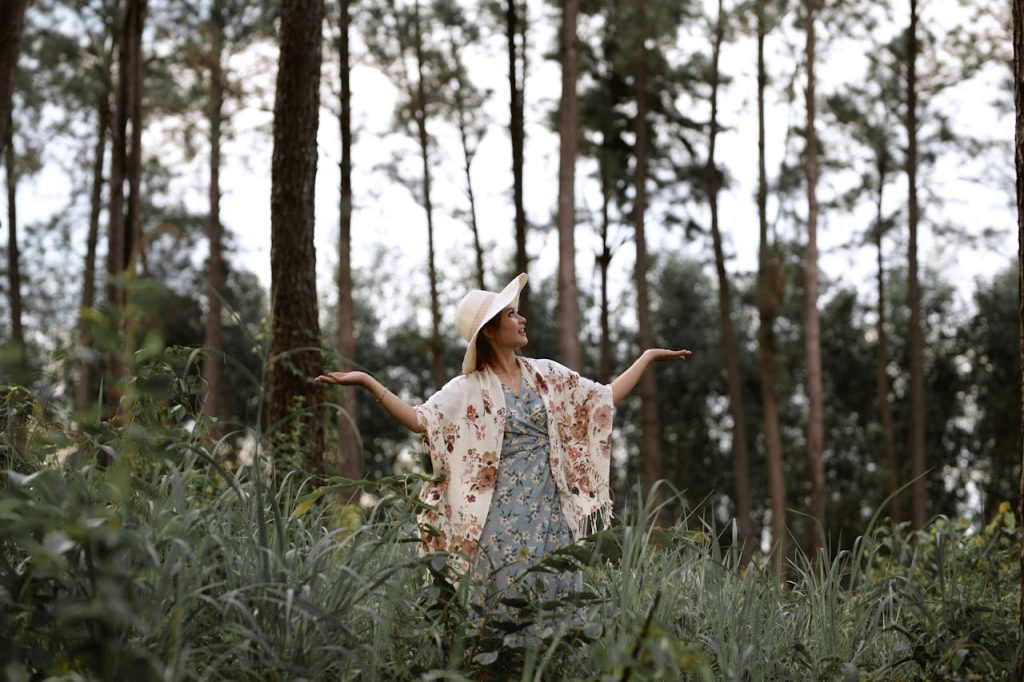 Woman in floral dress and hat exploring lush forest in Vietnam.